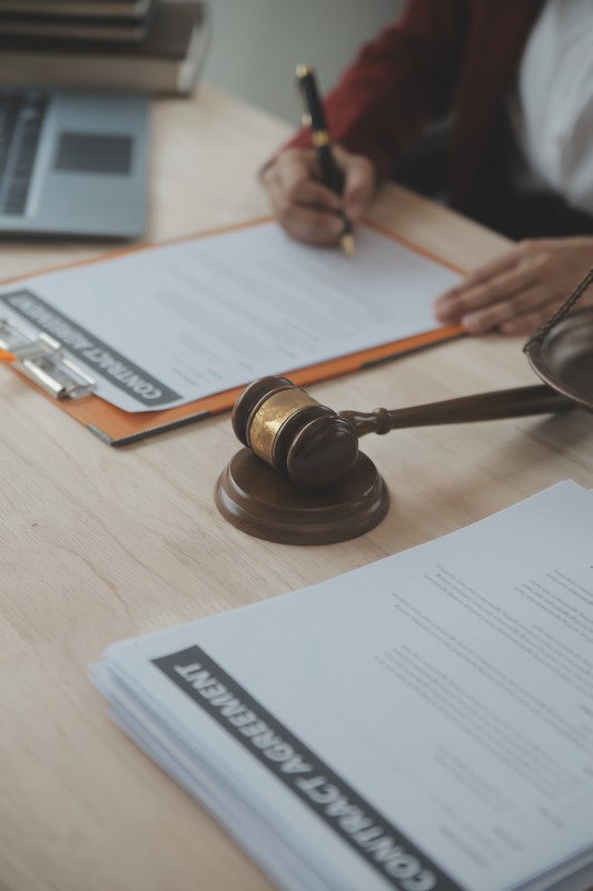 Business and lawyers discussing contract papers with brass scale on desk in office. Law, legal services, advice, justice and law concept picture with film grain effect