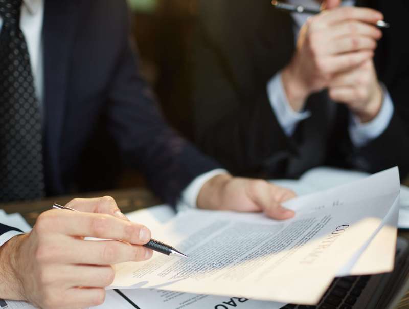Closeup shot of unrecognizable businessman reading contract documentation at meeting with financial partner